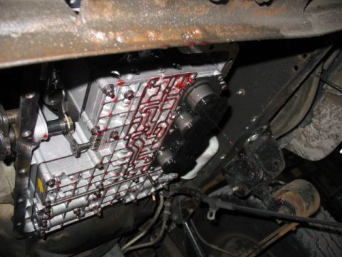 1995 Ford C-350 (Centurion Conversions) - Close-up view of a vehicle's automatic transmission valve body and pan, showing fluid residue.