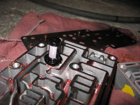 1995 Ford C-350 (Centurion Conversions) - Disassembled transmission valve body with filter and internal passages visible, red fluid present.