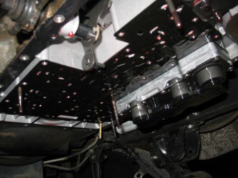 1995 Ford C-350 (Centurion Conversions) - Close-up of a vehicle's transmission valve body and removed pan, revealing internal components and fluid.