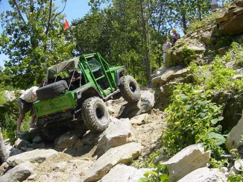 1992 Ford Bronco - An off-road vehicle navigates a challenging rocky incline on a sunny day.
