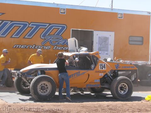 1990 Ford Bronco - orange off-road race buggy numbered 154 sits beside an orange race team trailer as crew members attend to it.