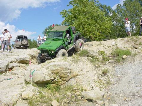 1992 Ford Bronco - Off-road vehicles navigate a challenging rocky course under a partly cloudy sky.