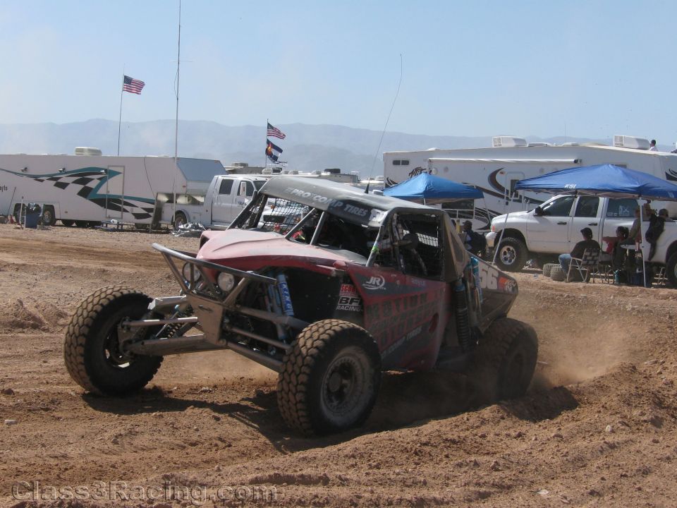 Red and silver off-road race buggy spraying dirt on track