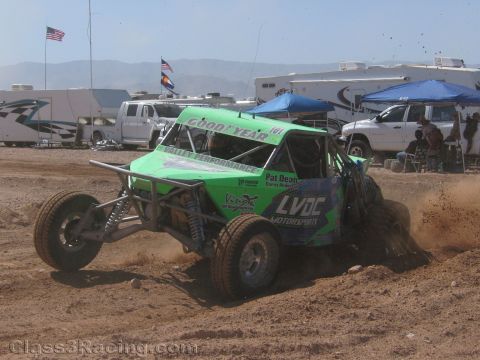 1990 Ford Bronco - green off-road race buggy numbered 161 with a Goodyear windshield banner sprays dirt while cornering on a dirt track.