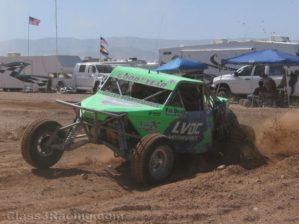 Green off-road race buggy #161 with Goodyear banner spraying dirt