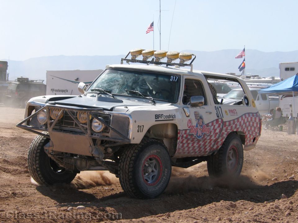 White and red checkered off-road race truck #317 with light bar on dirt