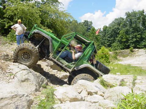 1992 Ford Bronco - An off-road vehicle navigates a challenging rocky incline with a driver and passenger inside.