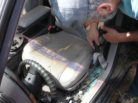 1989 Ford Taurus - The interior of a car shows significant damage with torn seats and shattered glass on the floor.