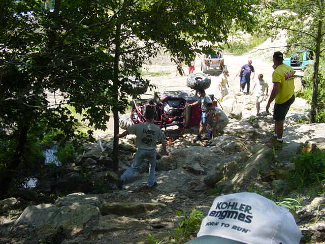Off-road vehicle on its side with people around