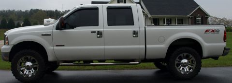 2006 Ford F-250 - A white 2006 Ford F-250 Super Duty FX4 pickup truck is parked in front of a house.