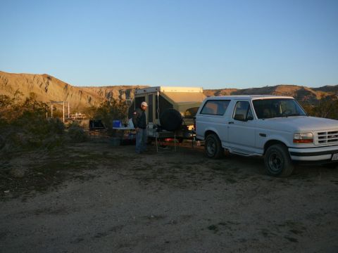 1988 Ford Bronco - A white 1995 Ford Bronco is parked in a desert setting next to a pop-up camper.