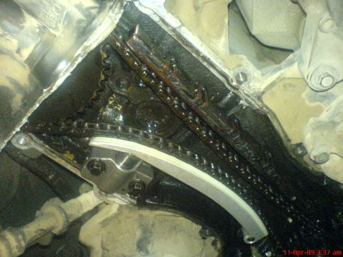 1992 Ford Crown Victoria - Close-up view of an engine's timing chain and tensioner, showing oil accumulation and wear.