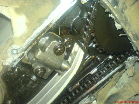 1992 Ford Crown Victoria - Close-up view of an engine's timing chain and tensioner mechanism, covered in oil.