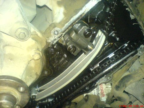 1992 Ford Crown Victoria - Close-up view of an engine's timing chain and tensioner mechanism, covered in oil.