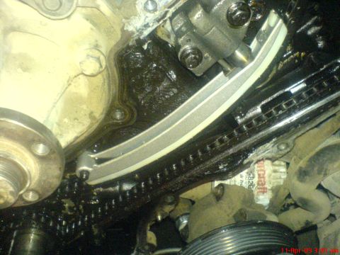 1992 Ford Crown Victoria - This image shows a close-up view of an engine's timing chain and tensioner assembly, covered in oil.