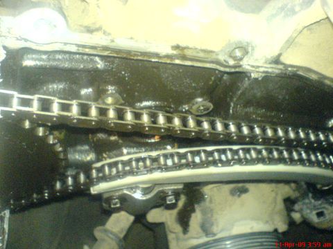 1992 Ford Crown Victoria - Close-up of an engine's timing chain and tensioner, showing oil buildup.