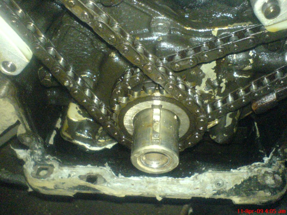 Close-up of engine timing chains and gears, with oil buildup