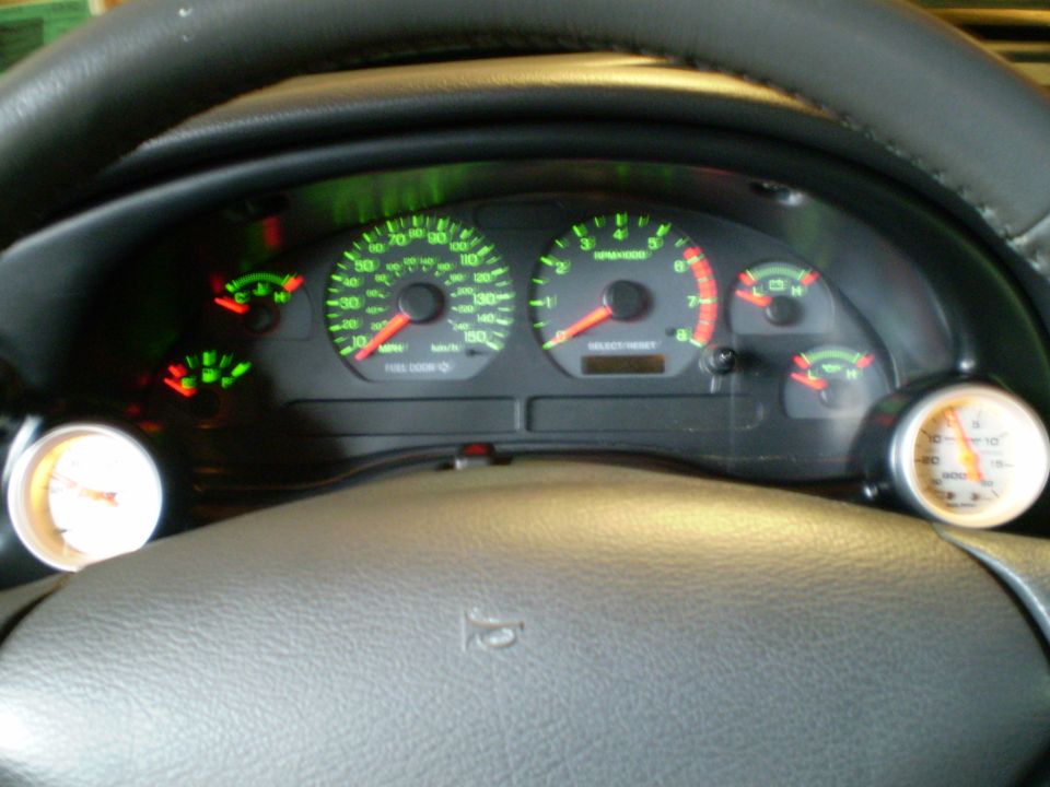 2002 Ford Mustang dashboard with speedometer, tachometer, fuel gauge, and two aftermarket gauges