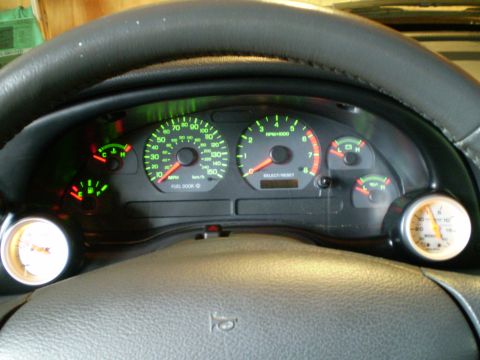 2002 Ford Mustang - The illuminated dashboard gauges and steering wheel are visible from the driver's perspective.
