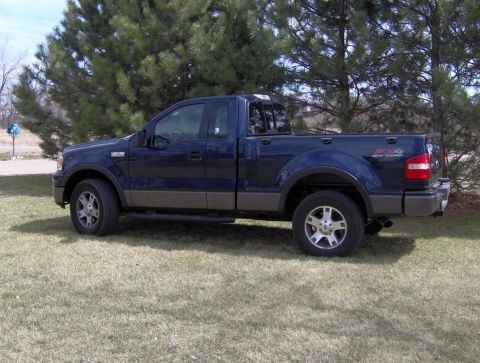 2005 Ford F-150 - This dark blue 2005 Ford F-150 pickup truck is seen from the side, parked on a grassy lawn.