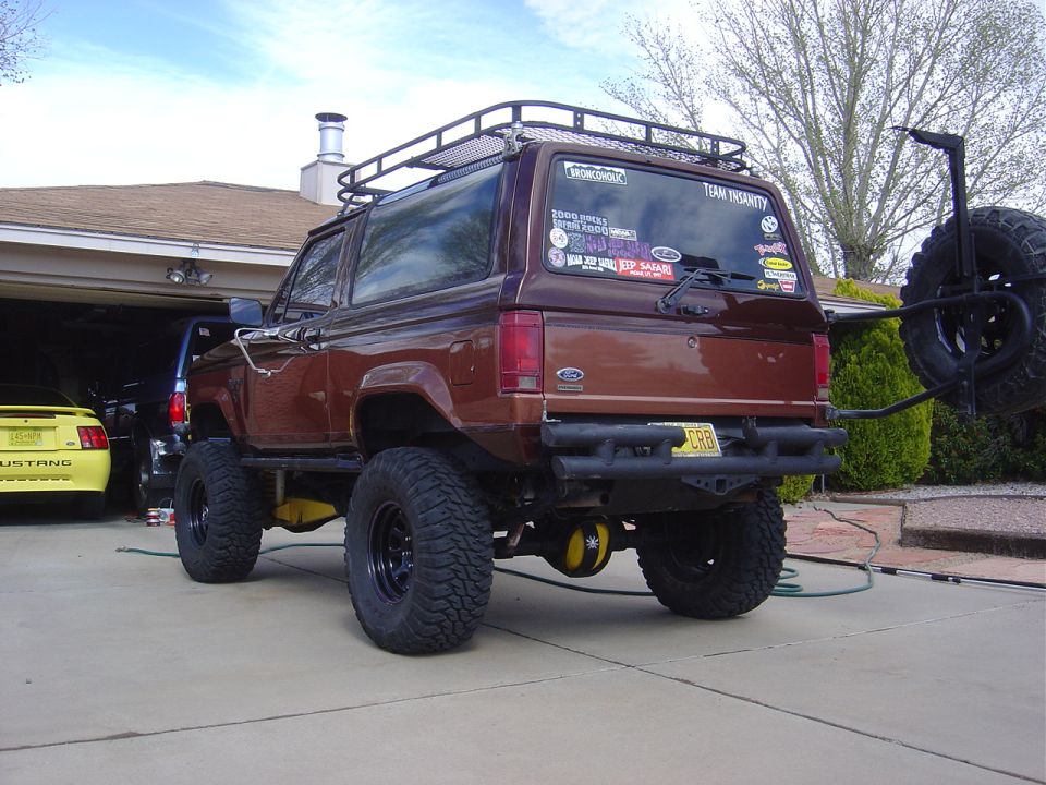 Brown Ford Bronco II with roof rack and spare tire carrier, lifted with large tires