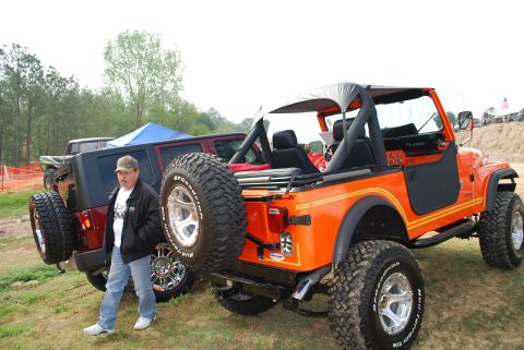 2008 Jeep Wrangler - Two Jeeps, an orange CJ-7 and a red Wrangler, parked outdoors with a man standing between them.
