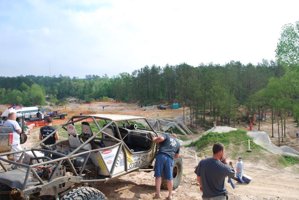 Off-road buggy with roll cage, mud tires, and custom bodywork, angled from the front-right