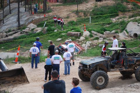 2008 Jeep Wrangler - Spectators watch as off-road vehicles navigate a challenging obstacle course with dirt and rocks.