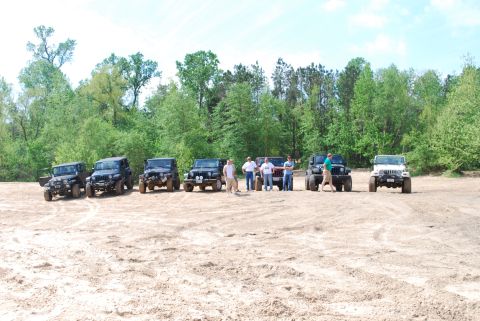 2008 Jeep Wrangler - Multiple Jeeps gathered in an outdoor sandy location with a wooded area behind them.