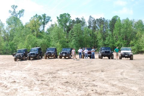 2008 Jeep Wrangler - A group of Jeep Wranglers are gathered together in an outdoor setting with a wooded area behind them.