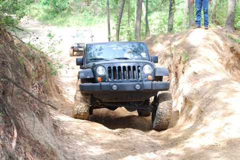 2008 Jeep Wrangler - Two Jeeps navigate a challenging off-road trail through a wooded area.