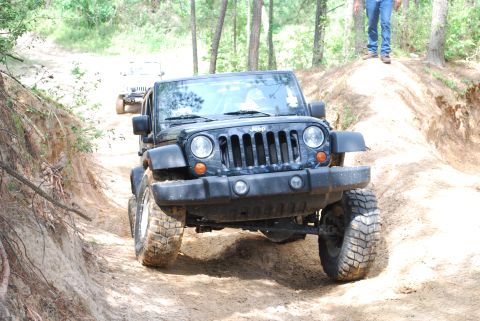 2008 Jeep Wrangler - A black Jeep Wrangler navigates a challenging dirt path with another Jeep visible in the background.