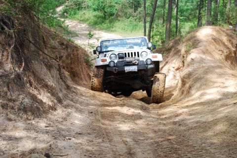 2008 Jeep Wrangler - A white 2008 Jeep Wrangler navigates a challenging dirt path, its off-road capabilities.