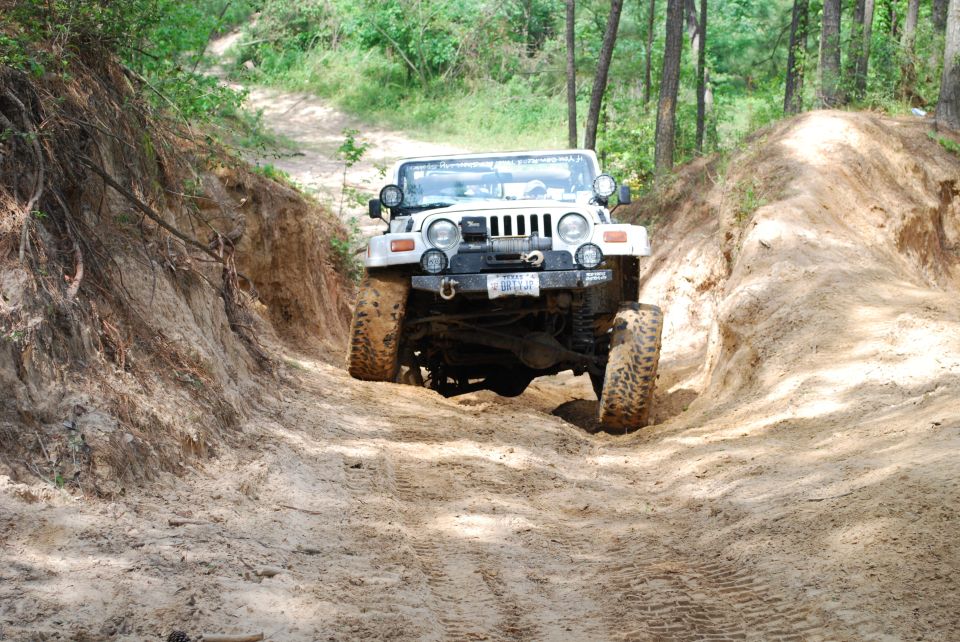 2008 Jeep Wrangler climbing a steep dirt path with trees on either side