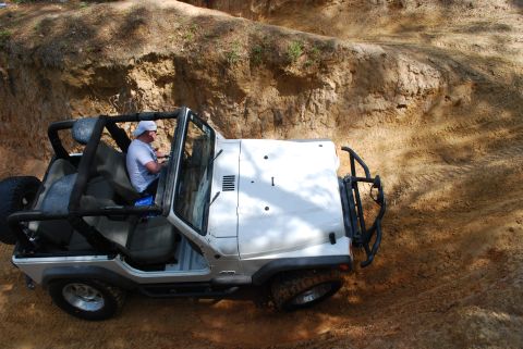 2008 Jeep Wrangler - A white Jeep Wrangler navigates a challenging off-road course, demonstrating its capabilities on rough terrain.