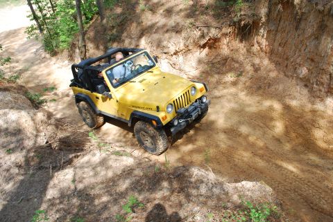 2008 Jeep Wrangler - A yellow Jeep Wrangler Rubicon navigates a steep, sandy off-road trail.