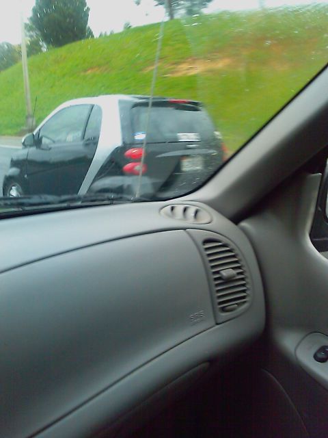 1996 Ford Bronco - Smart Fortwo driving on a road with a grassy embankment.