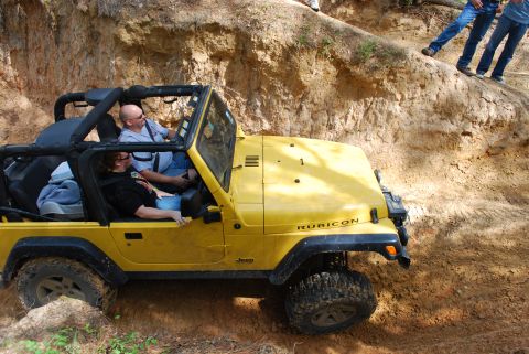 2008 Jeep Wrangler - A yellow Jeep Wrangler Rubicon navigates a steep dirt incline with occupants.