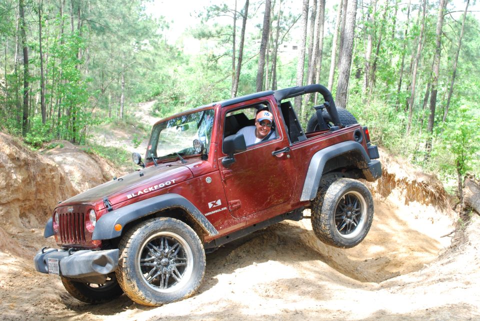 Red 2008 Jeep Wrangler JK with aftermarket wheels driving on a dirt trail