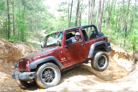 2008 Jeep Wrangler - A driver navigates a steep dirt incline in a red Jeep Wrangler during an off-road excursion.