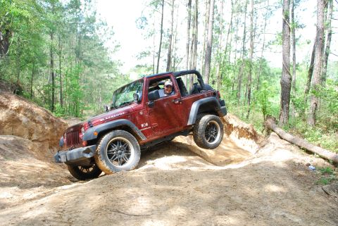 2008 Jeep Wrangler - A red Jeep Wrangler navigates an off-road trail, with a 'Blackfoot' decal on its fender.