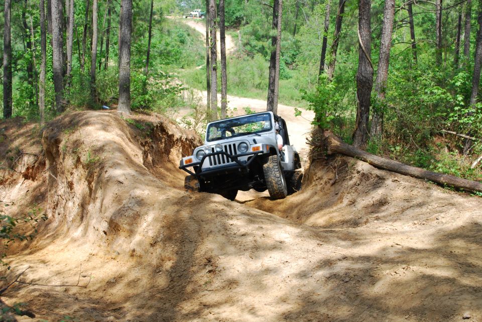 Silver 2008 Jeep Wrangler navigating a steep dirt incline on a wooded trail