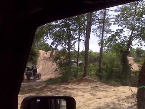 2008 Jeep Wrangler - Off-road vehicles navigate a challenging dirt track in a wooded area.