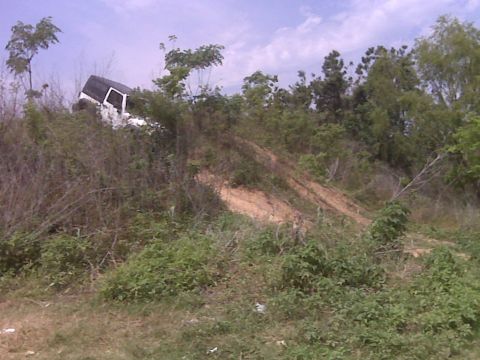2008 Jeep Wrangler - A white SUV is stuck on a steep, overgrown hill with a dirt track.