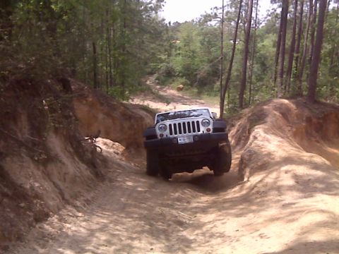 2008 Jeep Wrangler - A Jeep Wrangler navigates a challenging off-road trail with steep dirt banks.