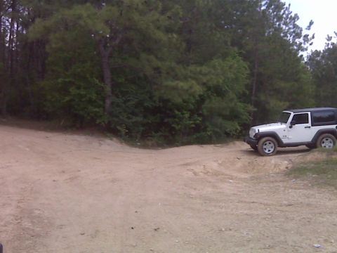 2008 Jeep Wrangler - A white Jeep Wrangler is parked on a dirt path surrounded by trees.