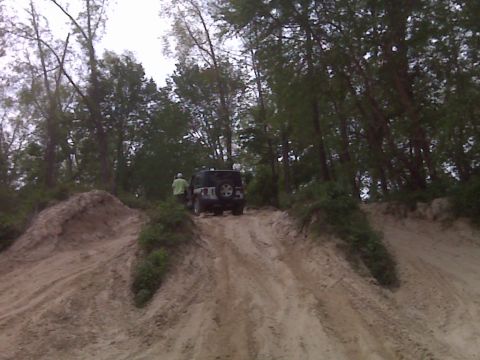 2008 Jeep Wrangler - A black Jeep Wrangler navigates a sandy incline surrounded by trees.
