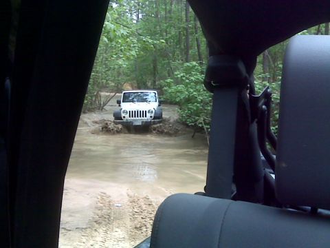 2008 Jeep Wrangler - White Jeep Wrangler navigating a muddy off-road trail.