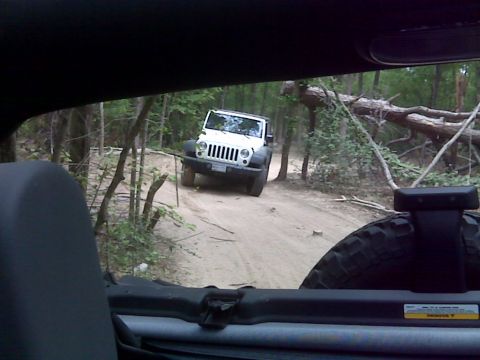 2008 Jeep Wrangler - A white 2007 Jeep Wrangler navigates a wooded trail, viewed from inside another vehicle.