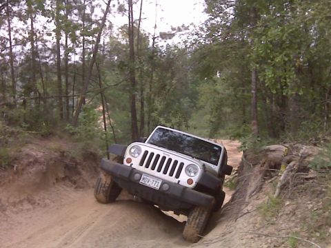 2008 Jeep Wrangler - White Jeep Wrangler navigating a challenging dirt trail in a wooded area.